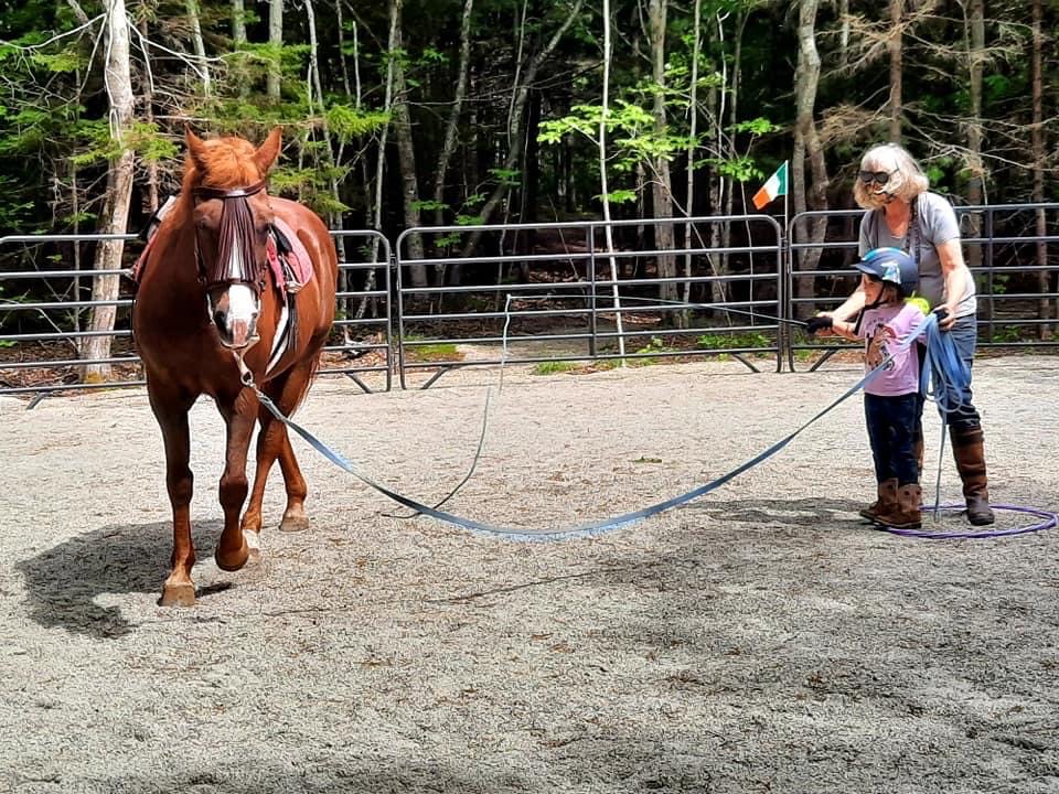 Women assisting child with a horse on a lunge line